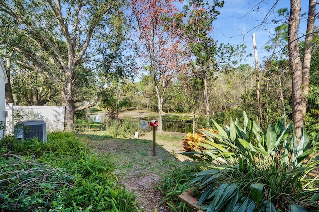 view of yard with a water view, fence, and central AC