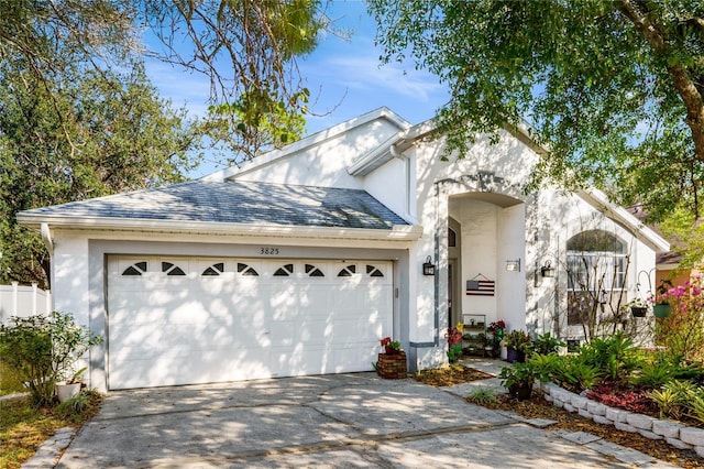 view of front of property with driveway, a shingled roof, a garage, and stucco siding