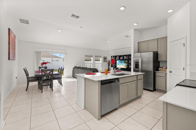 kitchen with gray cabinetry, a center island with sink, and appliances with stainless steel finishes