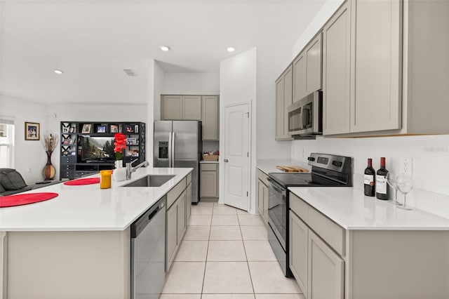 kitchen with gray cabinetry, sink, a center island with sink, and appliances with stainless steel finishes