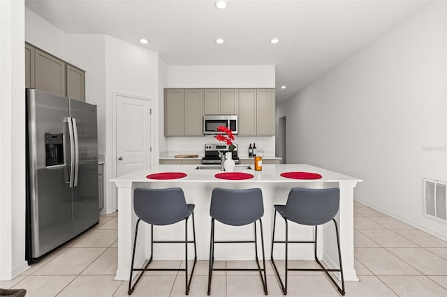 kitchen featuring appliances with stainless steel finishes, an island with sink, and light tile patterned floors