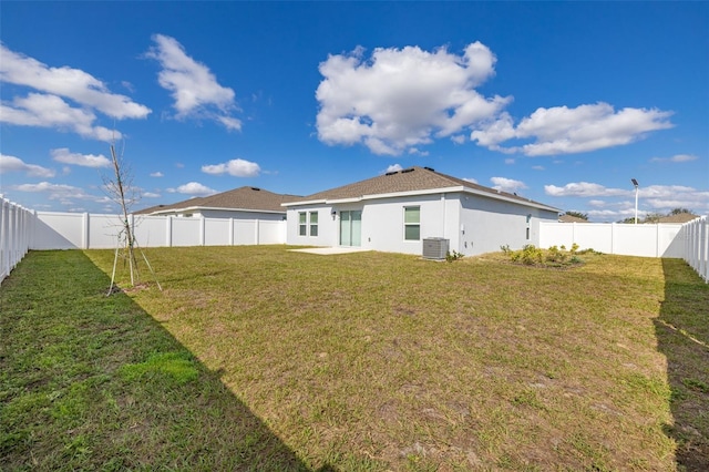 rear view of house featuring central AC and a lawn