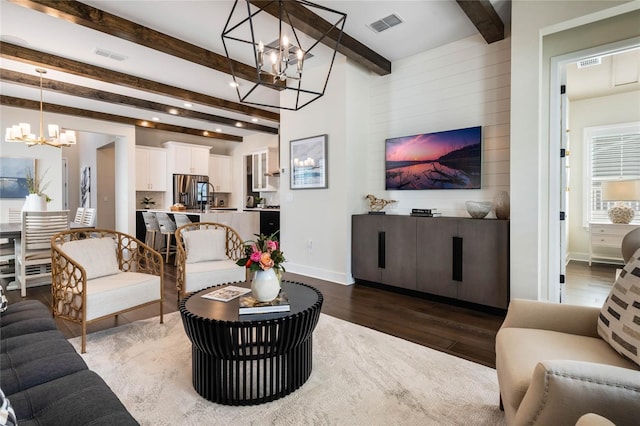 living room with an inviting chandelier, beam ceiling, and dark hardwood / wood-style flooring