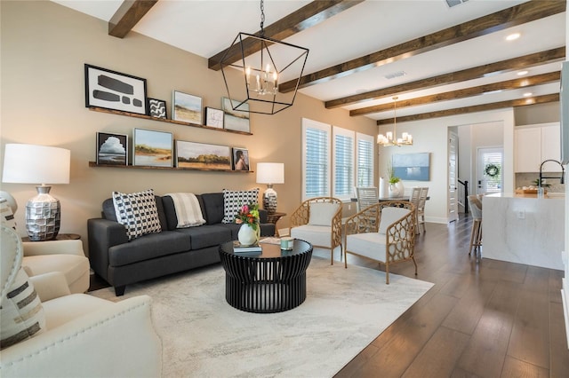 living room with beamed ceiling, wood-type flooring, a healthy amount of sunlight, and a chandelier