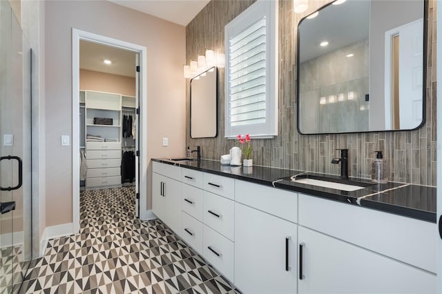 bathroom with vanity, a shower with door, and backsplash