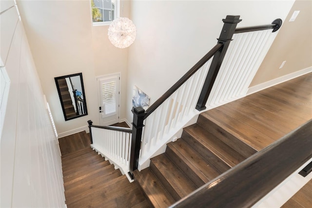 stairs featuring hardwood / wood-style flooring, a notable chandelier, and a high ceiling