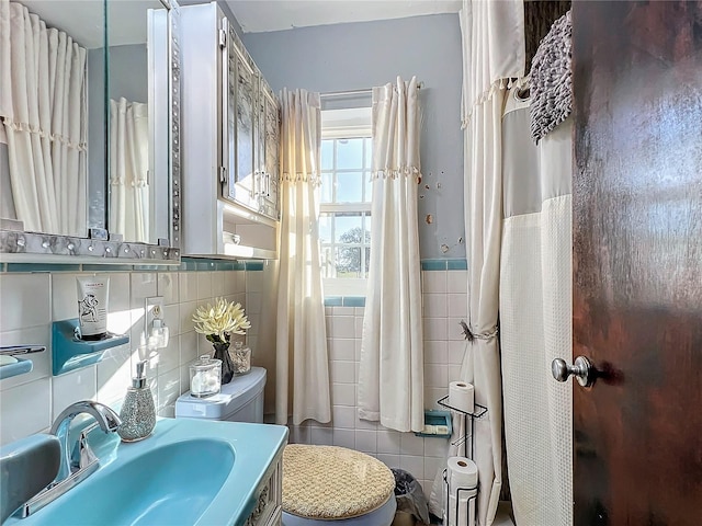 bathroom with tile walls, sink, and toilet