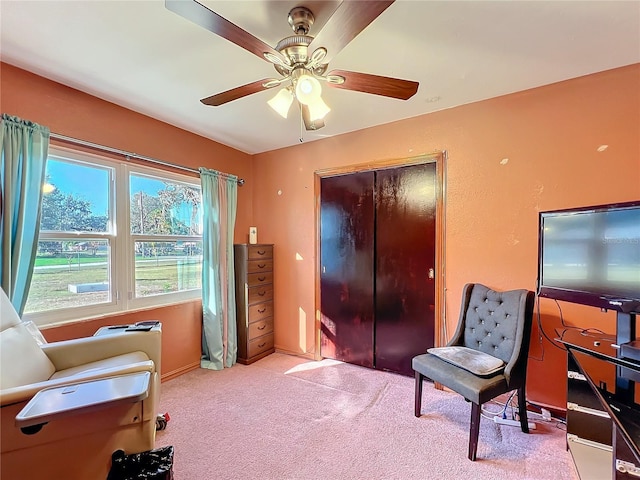 living area featuring light colored carpet and ceiling fan