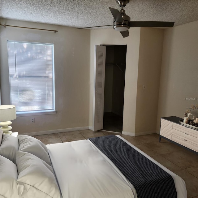 bedroom with ceiling fan, a closet, a textured ceiling, and light tile patterned flooring