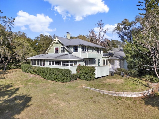 rear view of house featuring a sunroom and a lawn