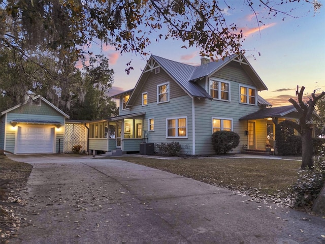 view of front of property featuring a garage, a sunroom, and cooling unit