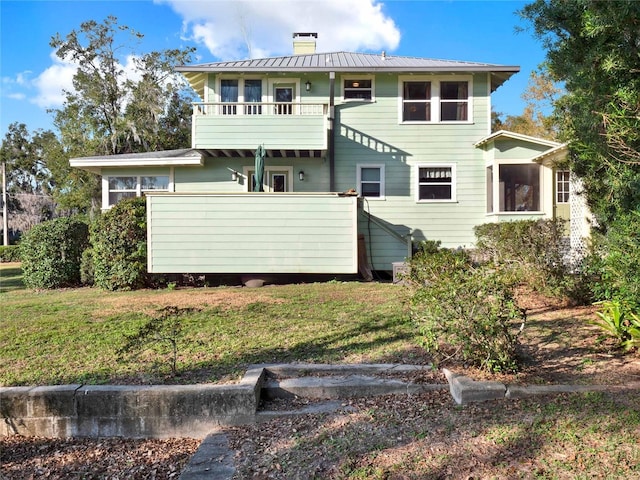 rear view of house featuring a balcony and a yard