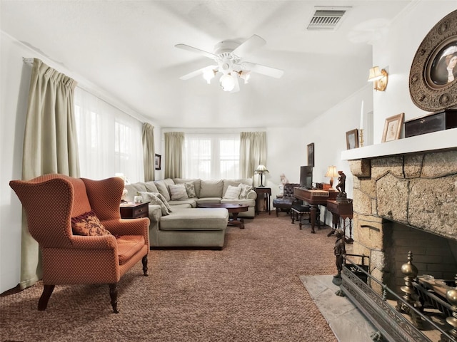 living room with ceiling fan, a stone fireplace, and light carpet