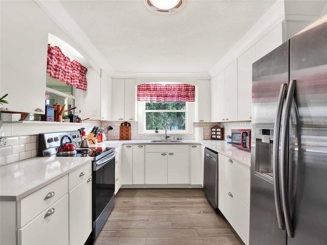 kitchen featuring sink, backsplash, stainless steel appliances, and white cabinets