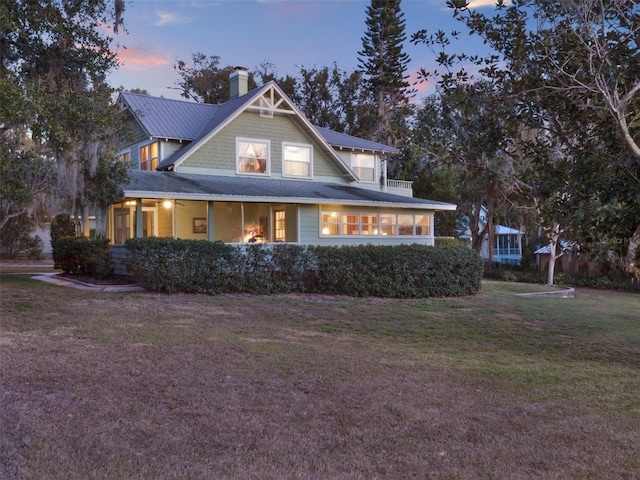 back house at dusk featuring a yard