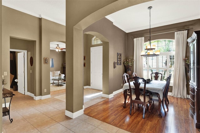 tiled dining area featuring crown molding, a towering ceiling, and ceiling fan