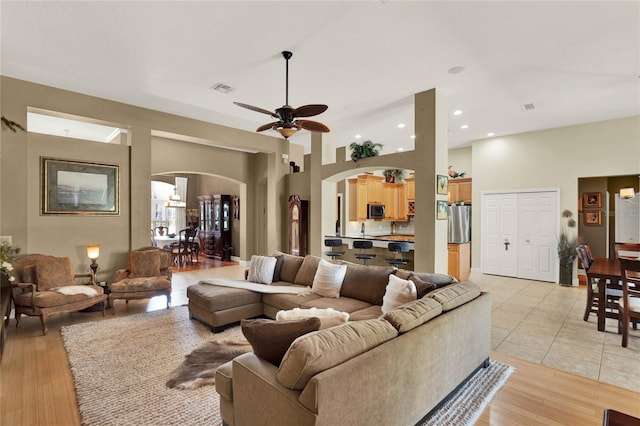 living room featuring ceiling fan, a towering ceiling, and light tile patterned floors