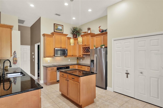 kitchen with appliances with stainless steel finishes, a center island, sink, and dark stone counters