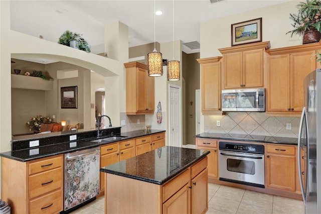 kitchen with sink, stainless steel appliances, kitchen peninsula, decorative light fixtures, and dark stone counters