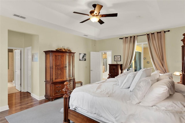 bedroom with access to exterior, dark hardwood / wood-style floors, a raised ceiling, and ceiling fan