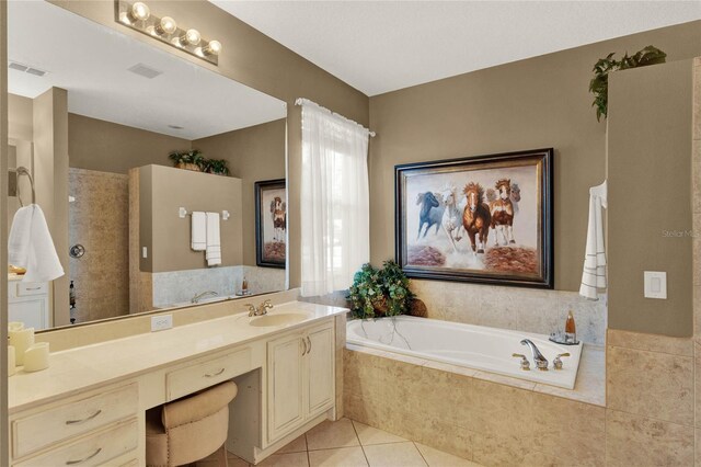 bathroom with tile patterned floors, vanity, and tiled bath