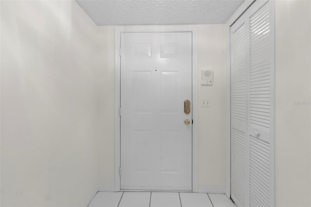 doorway to outside featuring a textured ceiling and light tile patterned flooring