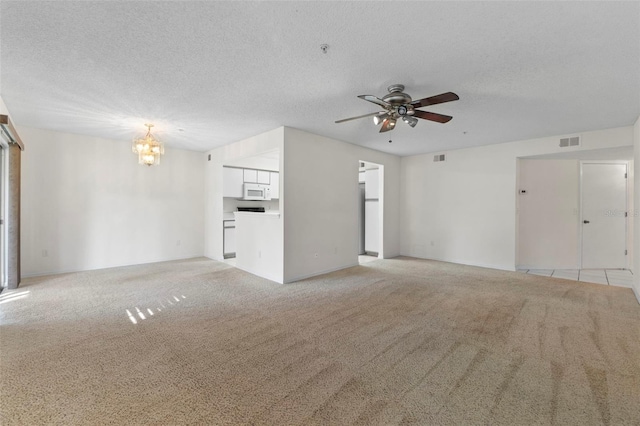 unfurnished living room featuring ceiling fan with notable chandelier, light carpet, and a textured ceiling