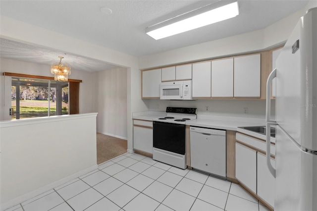 kitchen featuring light tile patterned floors, white appliances, white cabinets, decorative light fixtures, and a chandelier