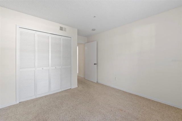 unfurnished bedroom with carpet floors, a closet, and a textured ceiling