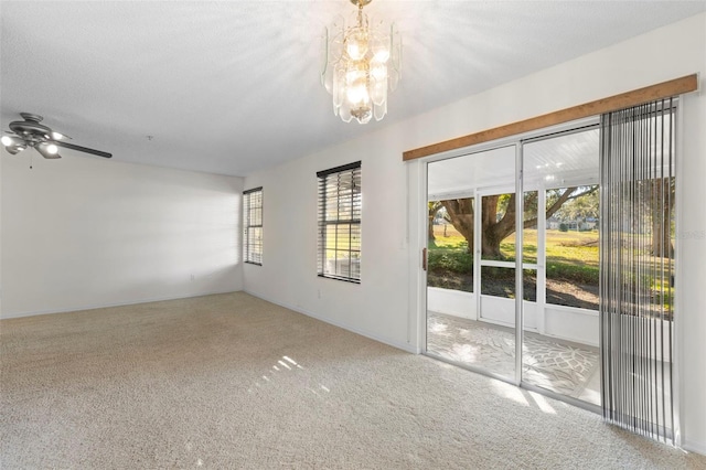 carpeted empty room featuring a notable chandelier and a textured ceiling