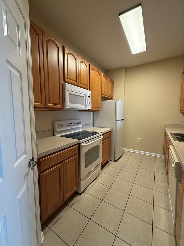 kitchen featuring sink, white appliances, and light tile patterned flooring