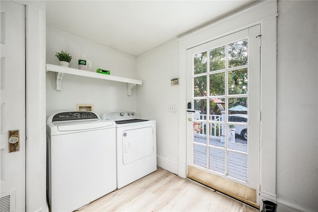 laundry area with washing machine and clothes dryer and light wood-type flooring