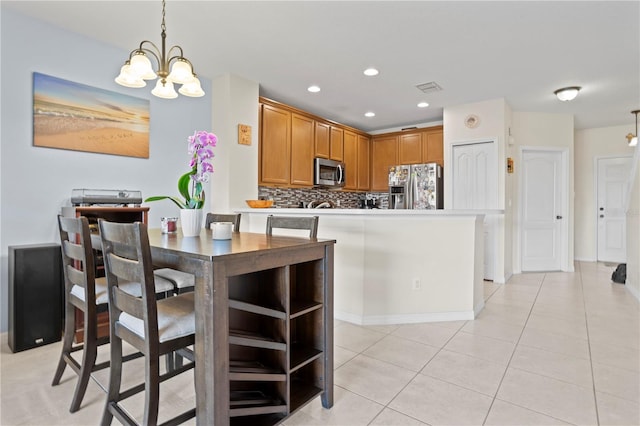 kitchen featuring tasteful backsplash, a chandelier, hanging light fixtures, light tile patterned floors, and stainless steel appliances