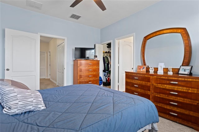 carpeted bedroom with a spacious closet, ceiling fan, and a closet