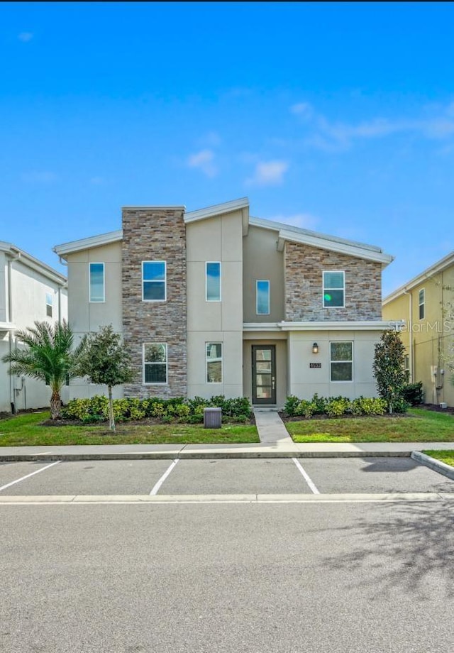 townhome / multi-family property featuring stone siding, central AC, and stucco siding