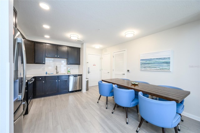 kitchen with backsplash, stainless steel appliances, sink, and light wood-type flooring