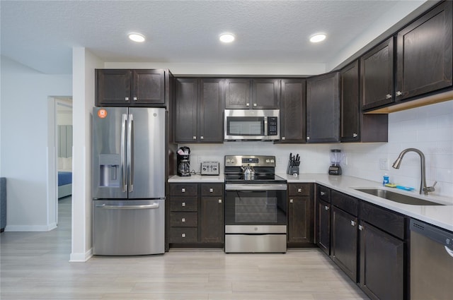 kitchen with dark brown cabinetry, sink, decorative backsplash, and stainless steel appliances