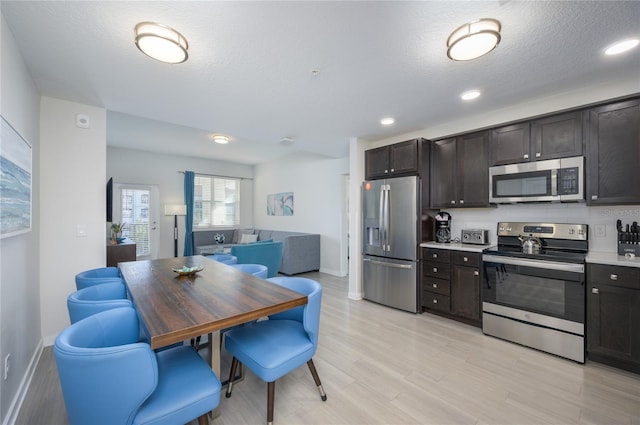 kitchen with dark brown cabinets, light hardwood / wood-style floors, a textured ceiling, and appliances with stainless steel finishes