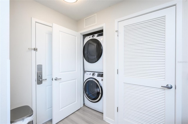 laundry area featuring light hardwood / wood-style flooring and stacked washer / dryer