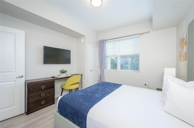 bedroom with built in desk and light wood-type flooring