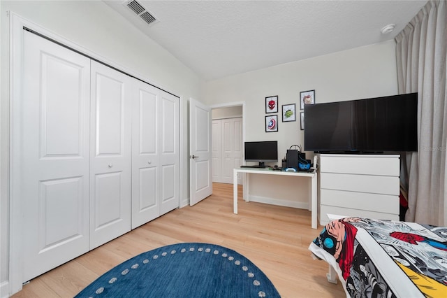 bedroom featuring hardwood / wood-style flooring, a textured ceiling, and a closet