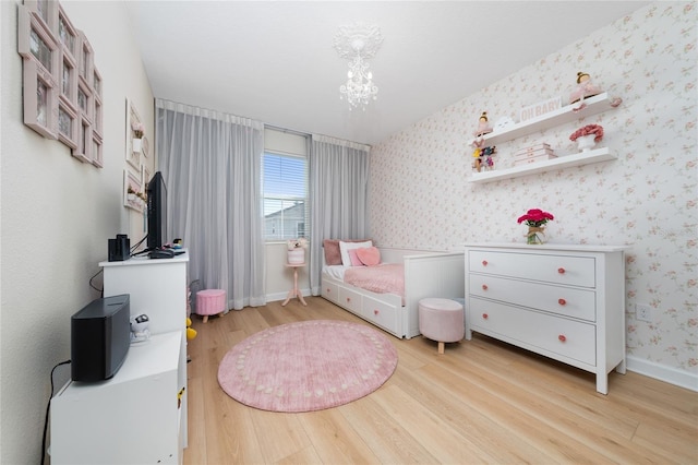 bedroom with a notable chandelier and light wood-type flooring