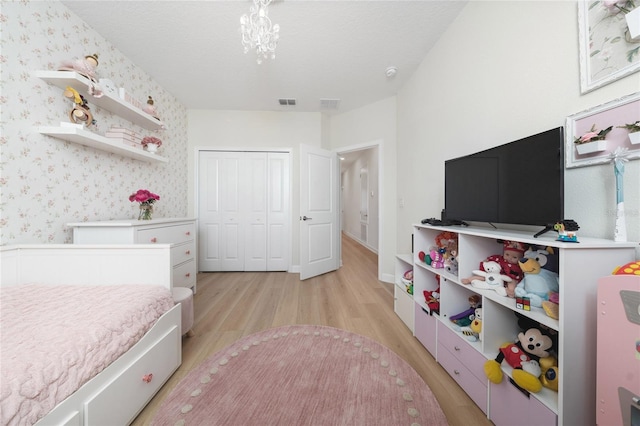 bedroom featuring a closet, a notable chandelier, light hardwood / wood-style flooring, and a textured ceiling