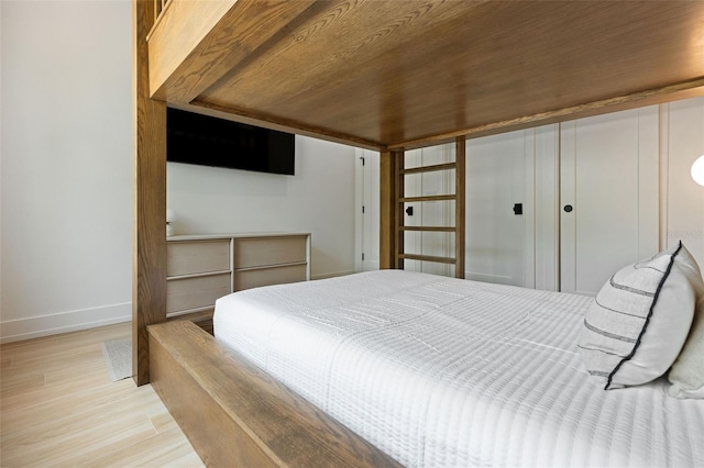 bedroom with light hardwood / wood-style floors, wood ceiling, and a closet