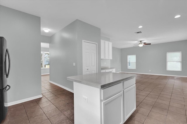 kitchen featuring white cabinetry, a center island, black refrigerator, and ceiling fan