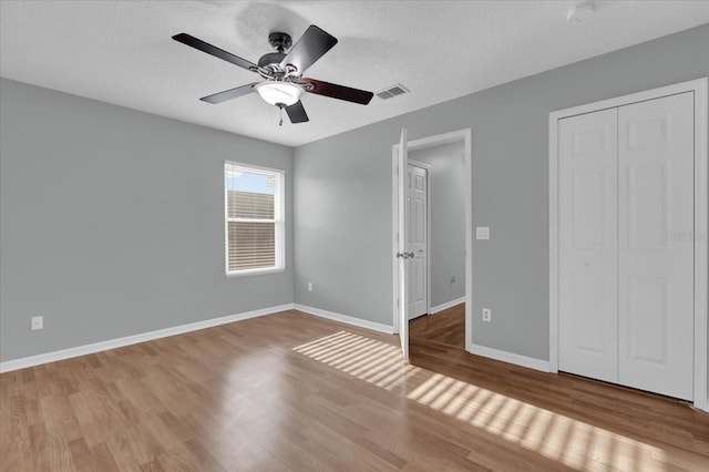 unfurnished bedroom with ceiling fan, light hardwood / wood-style floors, a closet, and a textured ceiling