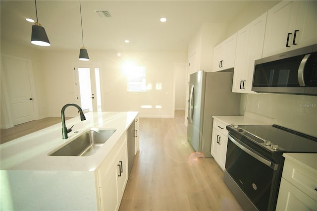 kitchen with sink, pendant lighting, stainless steel appliances, light hardwood / wood-style floors, and white cabinets