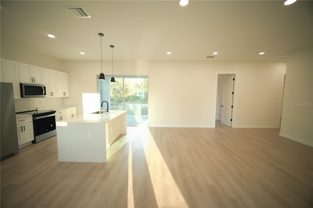 kitchen with white cabinetry, stainless steel appliances, sink, and an island with sink