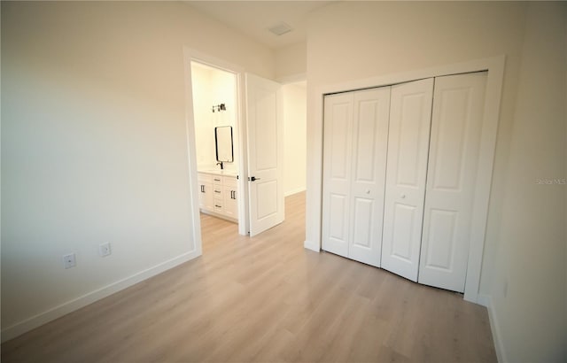 unfurnished bedroom featuring sink, light wood-type flooring, and a closet