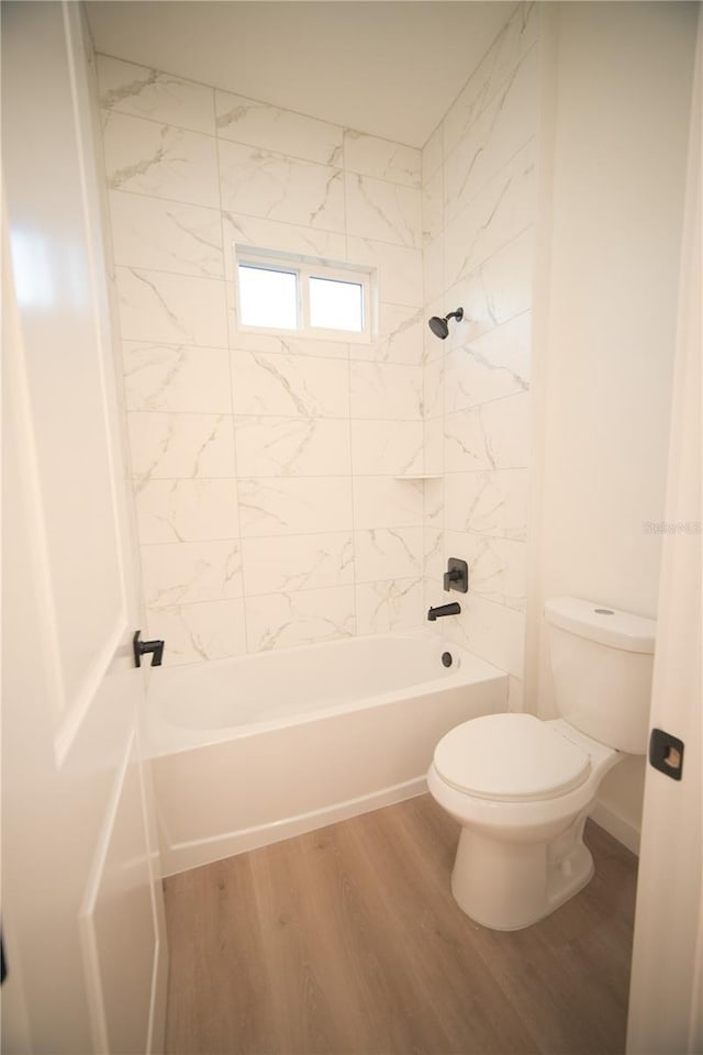 bathroom with tiled shower / bath, hardwood / wood-style floors, and toilet